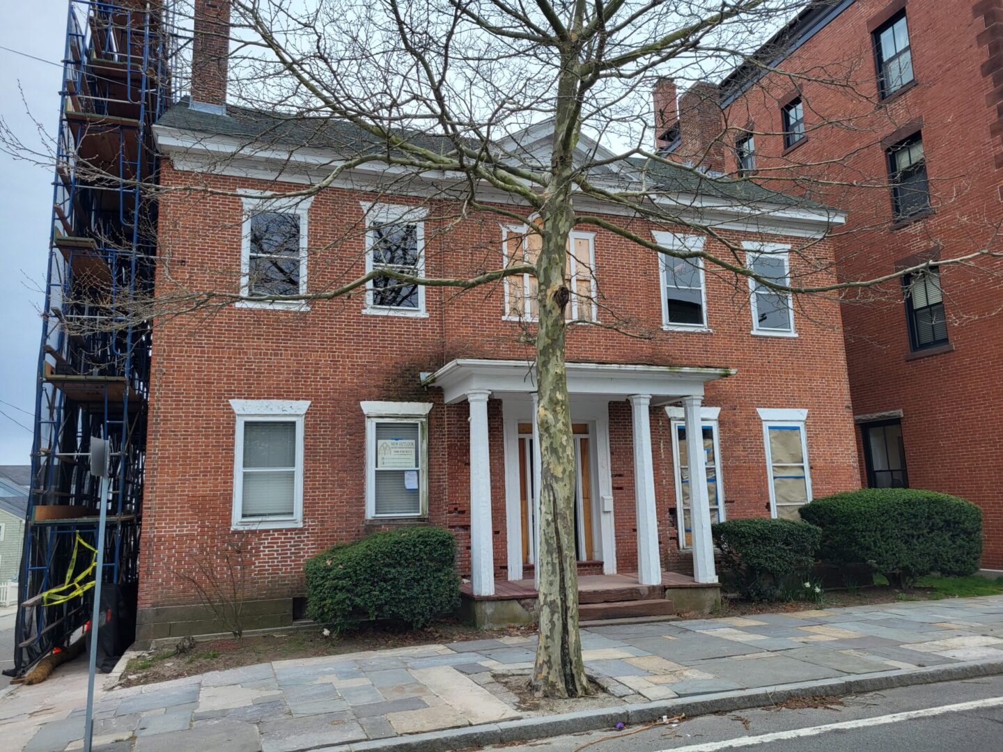 A brick building with two windows and a tree.